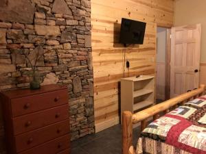 a bedroom with a stone wall with a bed and a tv at Private Cabin with Wi-Fi Nestled in the Mountains of Hiawassee, Georgia in Mountain Scene
