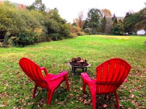 two red chairs and a fire pit in a field at Simple Cabin Camping for Families in the Catskills of Upstate New York in Big Indian +1 photo