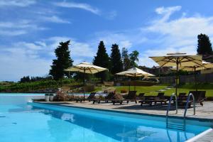 a swimming pool with umbrellas and chairs next to a pool at Villa San Filippo in Barberino di Val dʼElsa