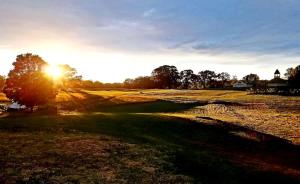 une vue d'un parcours de golf avec le soleil couchant dans l'établissement Rustic A-Frame Glamper near Nashville with Memory Foam Beds, Fire Pit & Country Breakfast, à Lebanon