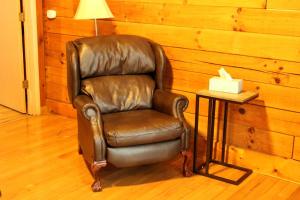 un fauteuil en cuir brun assis à côté d'une table de chevet dans l'établissement Secluded Cabin Rental near Watoga State Park in West Virginia, à Hico 7 autres photos