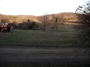 an open field with a barn in the distance at Historic Cabin Rental with Mountain Views in Potter County, Pennsylvania in Short Run