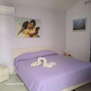 a bedroom with a purple bed with a picture on the wall at Villetta immersa nel verde in Piazza Armerina