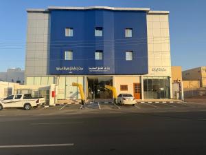 a blue building with cars parked in a parking lot at شقق دفادف المخدومة in Hail