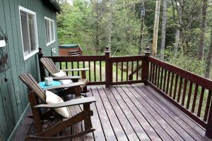 a wooden deck with two chairs and a table at Your Perfect Getaway: Mountain Cabin Retreat with Hot Tub and Fireplace in Lisbon, NH in Lisbon