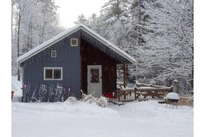 a blue building in the snow with a fence at Your Perfect Getaway: Mountain Cabin Retreat with Hot Tub and Fireplace in Lisbon, NH in Lisbon