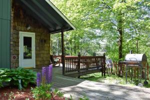 a porch of a cabin with a grill and flowers at Your Perfect Getaway: Mountain Cabin Retreat with Hot Tub and Fireplace in Lisbon, NH in Lisbon