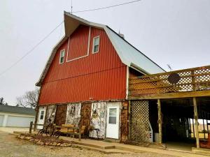 Une grande grange rouge avec une porte blanche dans l'établissement Rustic Barn Rental for a Rural Vacation near Des Moines, Iowa, à Montezuma