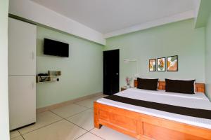 a bedroom with a bed and a tv on the wall at Super Collection O Jalpaiguri Railway Station Formerly Greater Kailash in Jalpāiguri