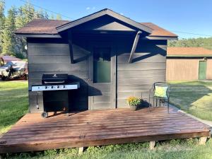 una barbacoa en una terraza con una casa en Cozy Tiny Cabin 8 in Rapid City, SD, en Hill City