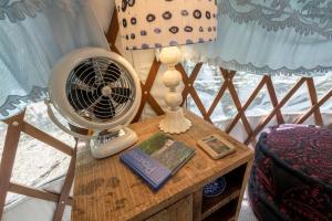 a table with a fan and a book and a lamp at Cozy Romantic Yurt Rental in Woodlands near California Beach Town of Cayucos in Cayucos +21 photos