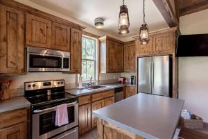 a kitchen with wooden cabinets and a stainless steel refrigerator at Two-Bedroom Cabin Rental with Fully Equipped Kitchen near Fredericksburg, Texas in Quinlan