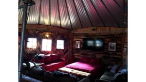 - un salon avec des meubles rouges dans une cabane en rondins dans l'établissement Rustic Octagon-Shaped Cabin for a Glamping Getaway near Huntington, West Virginia, à Genoa