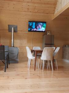Kinchkha cottage Fshuqebi - კინჩხის კოტეჯი ფშუქები في Kinchkha-Perdi: غرفة طعام مع طاولة وتلفزيون على الحائط