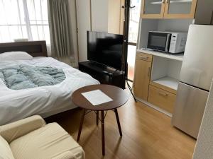 会津若松市にあるサムライ シティ イン 信夫屋のベッドとテーブルとテレビのある寝室