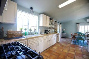 Pet Friendly Fantastic Secluded Cottage with Hot-tub in Rainbow, California في Rainbow: مطبخ فيه دواليب بيضاء وطاولة فيه