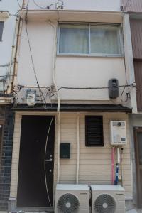 ein Haus mit einer Tür und zwei Klimaanlagen in der Unterkunft Osaka Tengachaya Guesthouse SAYURI 3号館 in Wada