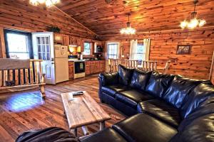 a living room with a leather couch and a table at Charming Log Cabin with a Fire Pit in the Woods near Lake Logan in Ohio in Cedar Grove