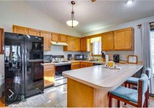 a kitchen with wooden cabinets and a black refrigerator at Charming Cabin on Golf Course with Fireplace & Resort Perks in Hedgesville, West Virginia in Baxter