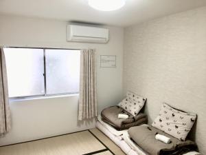 ein kleines Zimmer mit einem Sofa und einem Fenster in der Unterkunft Osaka Tengachaya Guesthouse SAYURI 3号館 in Wada