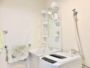 ein weißes Badezimmer mit Waschbecken und Spiegel in der Unterkunft Osaka Tengachaya Guesthouse SAYURI 3号館 in Wada