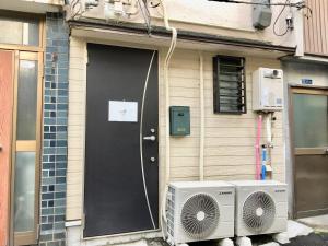 eine Haustür mit einem Ventilator in der Unterkunft Osaka Tengachaya Guesthouse SAYURI 3号館 in Wada + 5 Fotos