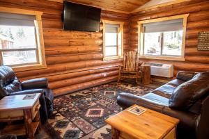 a living room with leather furniture in a log cabin at Spacious Luxury Cabin with Bunk Room & Nature Trail Access near Bonners Ferry, Idaho in Bonners Ferry