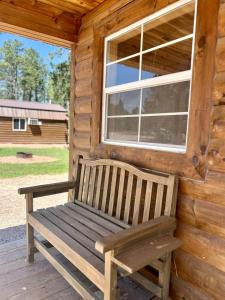 a wooden bench sitting on the porch of a cabin at Unique Wooden Cabin Nestled Amidst Trees in Rapid City, South Dakota in Rockerville