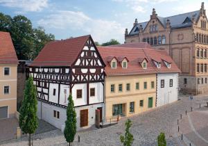a building with a red roof next to other buildings at Pößnecker Werkstätten -Tessenow Wohnung in Pößneck