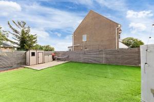 einen Hinterhof mit grünem Rasen vor einem Haus in der Unterkunft Brand New Luxurious 3bed House in Northfleet