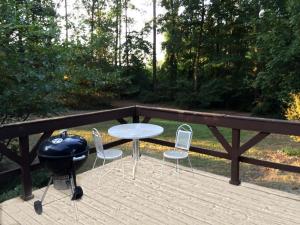 a grill and chairs and a table on a deck at Peaceful and Secluded Lake Getaway in Guntersville, Alabama in Albertville