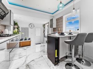 eine Küche mit Theke und einer Insel mit Stühlen in der Unterkunft Brand New Luxurious 3bed House in Northfleet