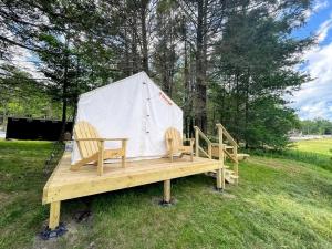 two wooden benches with a tent in a field at Romantic Safari Tent Surrounded by Trees Next to the Lake for a Unique Glamping Getaway in Lake Ariel, Pennsylvania in Arlington