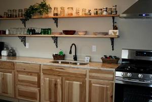 a kitchen with wooden cabinets and a sink and a stove at Secluded Cabin with River and Mountain Views near Columbus, Montana in Nye