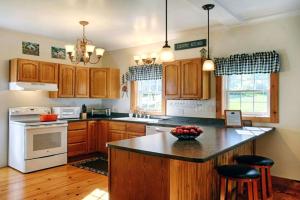 a kitchen with wooden cabinets and a black counter top at Light-Filled, Well-Appointed Mountain Cabin for a Vacation in Wells, Vermont in Wells