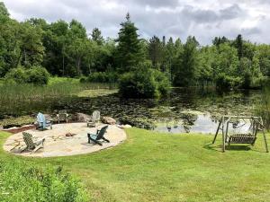 ein Park mit Stühlen und einem Spielplatz neben einem Teich in der Unterkunft Gorgeous Green Mountain Retreat for a Family Vacation in Vermont in Mount Holly