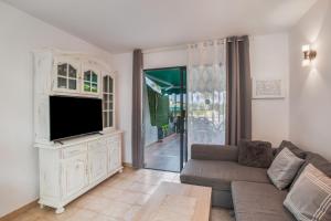 Una sala de estar con un sofá y un televisor. en Great Bungalow Maspalomas, en Maspalomas