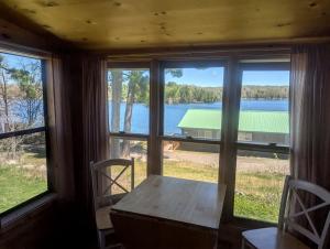 a table and chairs in a room with a large window at Calming Cabin Rental with Lake Views near Nicolet National Forest, Wisconsin in New Post