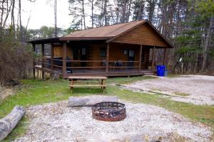 eine Blockhütte mit einem Picknicktisch und einer Bank in der Unterkunft Secluded Log Cabin with a Hot Tub near Bridle Trails in Logan, Ohio in Cedar Grove
