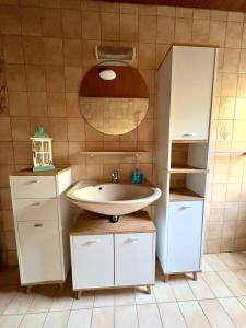 a bathroom with a sink and cabinets and a shelf at Frisch renovierte Ferienwohnung in Bad Schönborn in Bad Schonborn