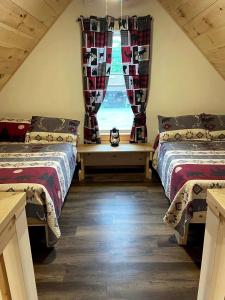 une chambre mansardée avec deux lits et une fenêtre dans l'établissement Cozy Secluded Cabin with Fire Pit and Barbecue in Greenville, Maine, à Greenville