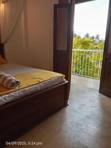 a bedroom with a bed with a view of a balcony at Villa Auro in Hikkaduwa