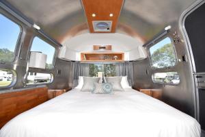 a bed in the middle of a room with two windows at Classy Airstream Land Yacht Rental with Modern Amenities near Gatlinburg, Tennessee in Shady Grove