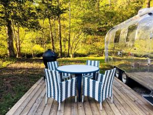a table and chairs on a deck next to an rv at Classy Airstream Land Yacht Rental with Modern Amenities near Gatlinburg, Tennessee in Shady Grove