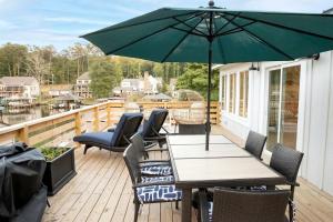 un patio avec une table, des chaises et un parasol dans l'établissement Stunning Modern Lakehouse with Private Boat Dock in Norwood, North Carolina, à Norwood