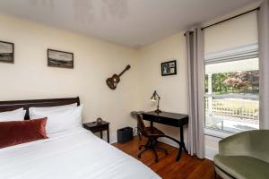 a bedroom with a bed and a desk and a guitar on the wall at Exquisite Zen Suite Retreat near Blue Ridge Mountain in Virginia in Luray