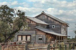 an old wooden barn with a fence in front of it at 1800's Antique Log Cabin with Modern Amenities near Fredericksburg and Kerrville, Texas in Hunt