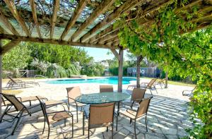 a patio with a table and chairs and a pool at 1800's Antique Log Cabin with Modern Amenities near Fredericksburg and Kerrville, Texas in Hunt