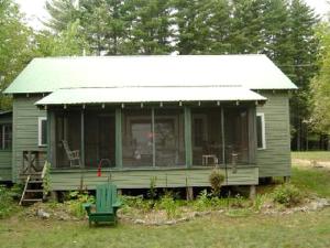 une petite maison verte avec un toit blanc dans l'établissement Nestled Camping Cabin Rental Overlooking Lake near Glens Falls, New York, à Severance