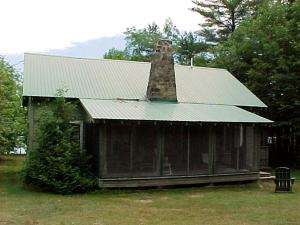 une vieille maison avec une cheminée en briques au sommet dans l'établissement Nestled Camping Cabin Rental Overlooking Lake near Glens Falls, New York, à Severance